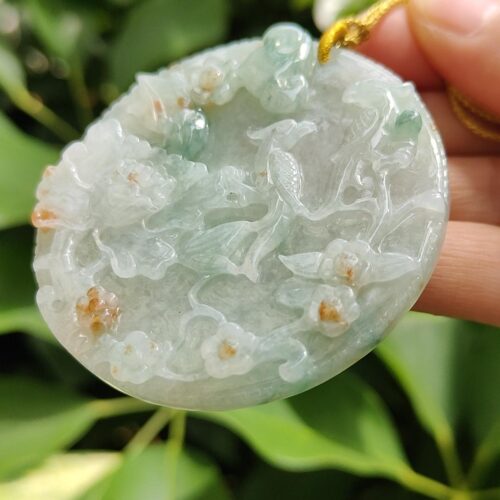 a hand holding a jade pendant