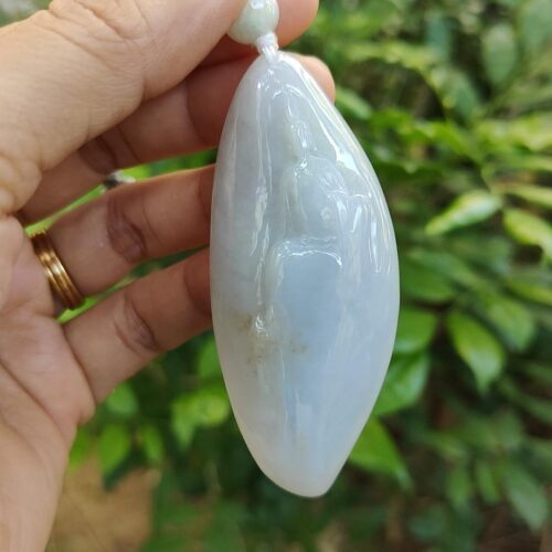 une main tenant un pendentif en pierre blanche