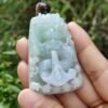 une main tenant un pendentif en jade