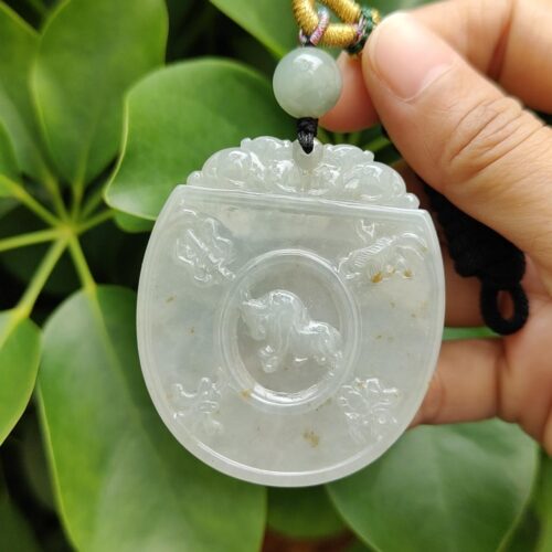 une main tenant un pendentif en jade