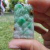 a hand holding a jade pendant
