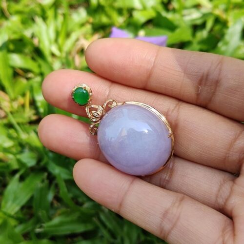 a hand holding a purple and gold pendant