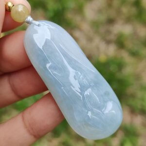 Una mano sosteniendo un colgante de jade azul.