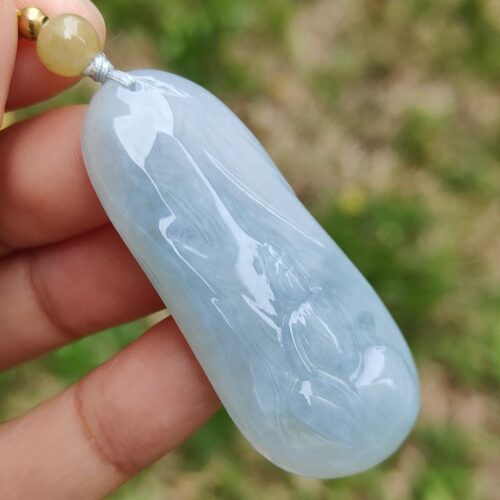 Una mano sosteniendo un colgante de jade azul.