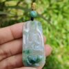 a hand holding a jade pendant