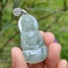 a hand holding a jade buddha pendant