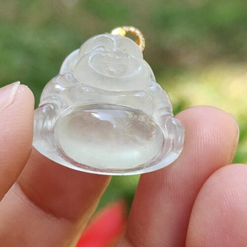 a hand holding a small white buddha pendant