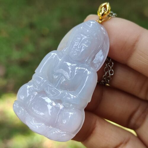 a hand holding a jade pendant