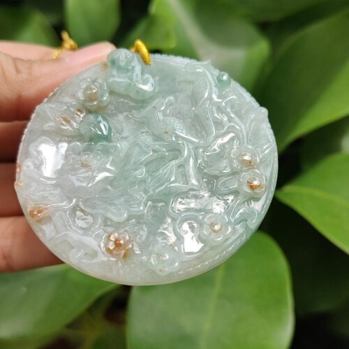 a hand holding a round object with a gold thread