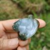 a hand holding a small frog shaped stone
