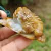 a hand holding a small frog shaped stone