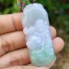 a hand holding a jade pendant