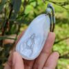 a hand holding a jade pendant