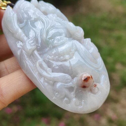 एक हाथ में सफ़ेद पत्थर का पेंडेंट है