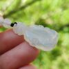 a hand holding a white jade necklace