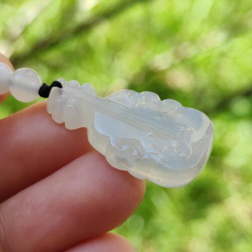 a hand holding a white jade necklace