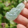 a hand holding a jade pendant