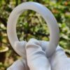a hand in a glove holding a white ring