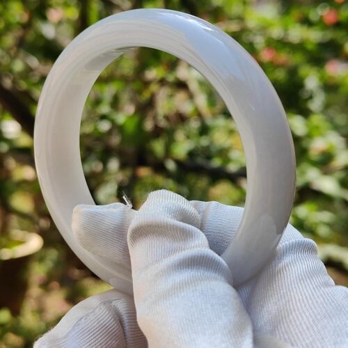 a hand in a glove holding a white ring