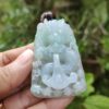 une main tenant un pendentif en jade