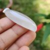 a hand holding a white oval shaped stone