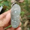une main tenant un pendentif en jade