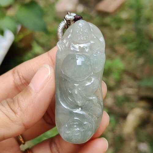 une main tenant un pendentif en jade