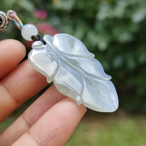 a hand holding a white leaf pendant