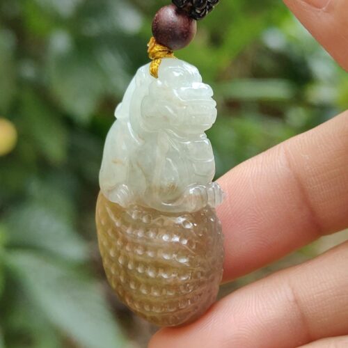 une main tenant un pendentif en jade
