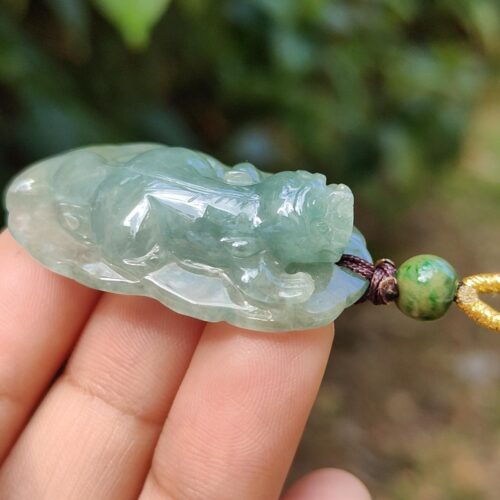a hand holding a jade pendant