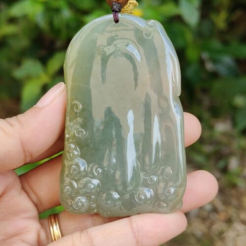 a hand holding a jade pendant
