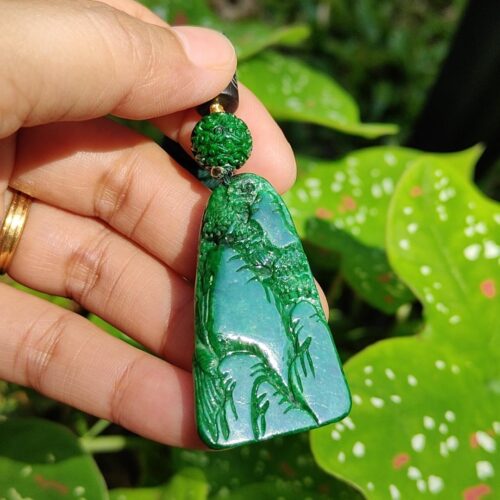 a hand holding a green pendant