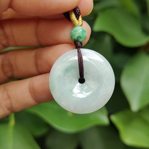 une main tenant un pendentif en jade