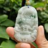 a hand holding a jade pendant