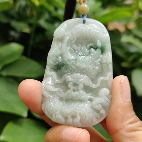 a hand holding a jade pendant