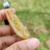 a hand holding a yellow stone necklace
