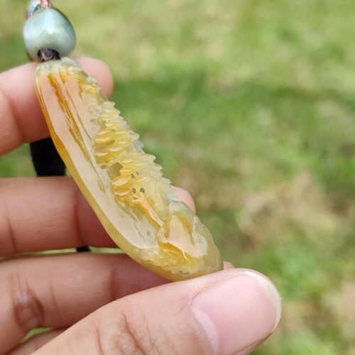a hand holding a yellow stone necklace