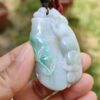 a hand holding a jade pendant