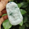 a hand holding a jade pendant