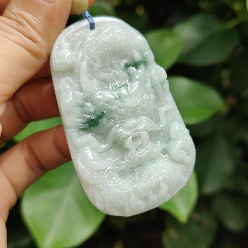 a hand holding a jade pendant