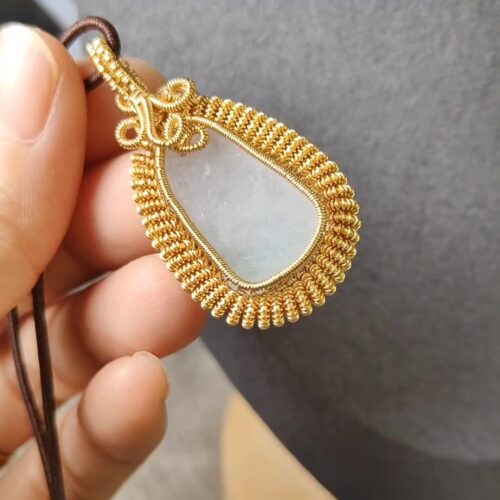 एक हाथ में सोने और सफेद पत्थर का पेंडेंट है