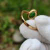 a hand wearing a glove holding a gold ring
