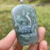 a hand holding a jade pendant