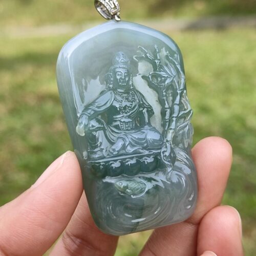 a hand holding a jade pendant