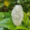 a white jade pendant on a green leaf