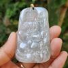 a hand holding a jade pendant