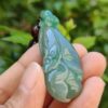 Una mano sosteniendo un colgante de jade.