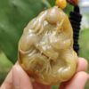 a hand holding a jade pendant