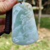 a hand holding a jade pendant