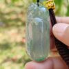 Una mano sosteniendo un colgante de jade.